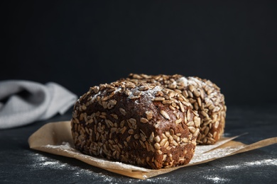 Photo of Fresh wholegrain bread on table against black background, closeup