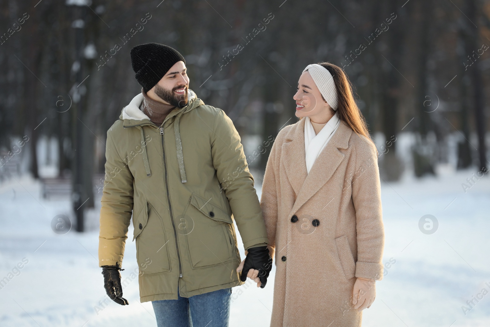 Photo of Beautiful happy couple walking in snowy park on winter day