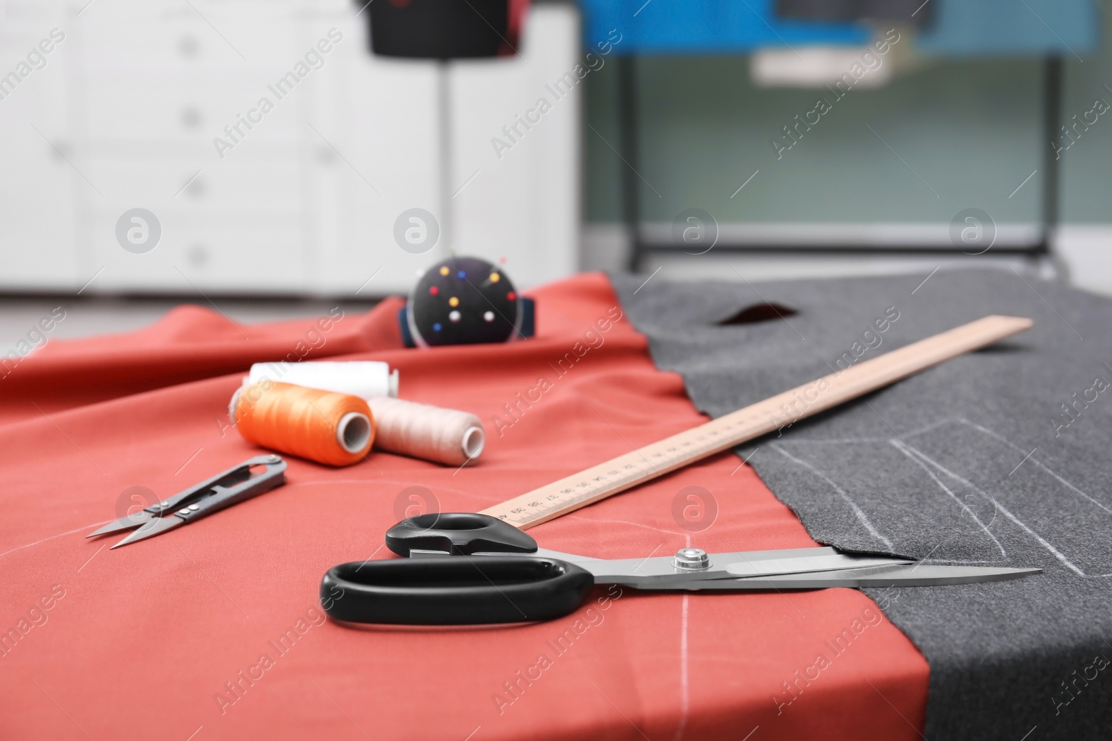 Photo of Fabric and sewing tools on table in tailor workshop