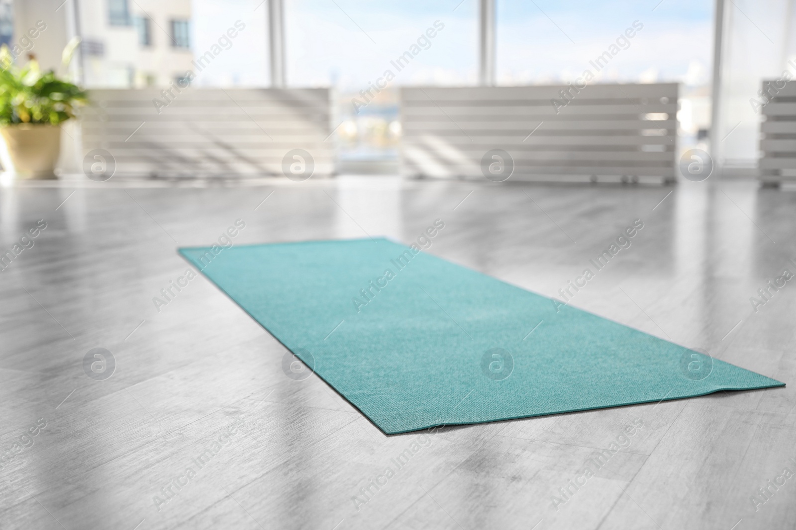 Photo of Unrolled light blue yoga mat on floor in room