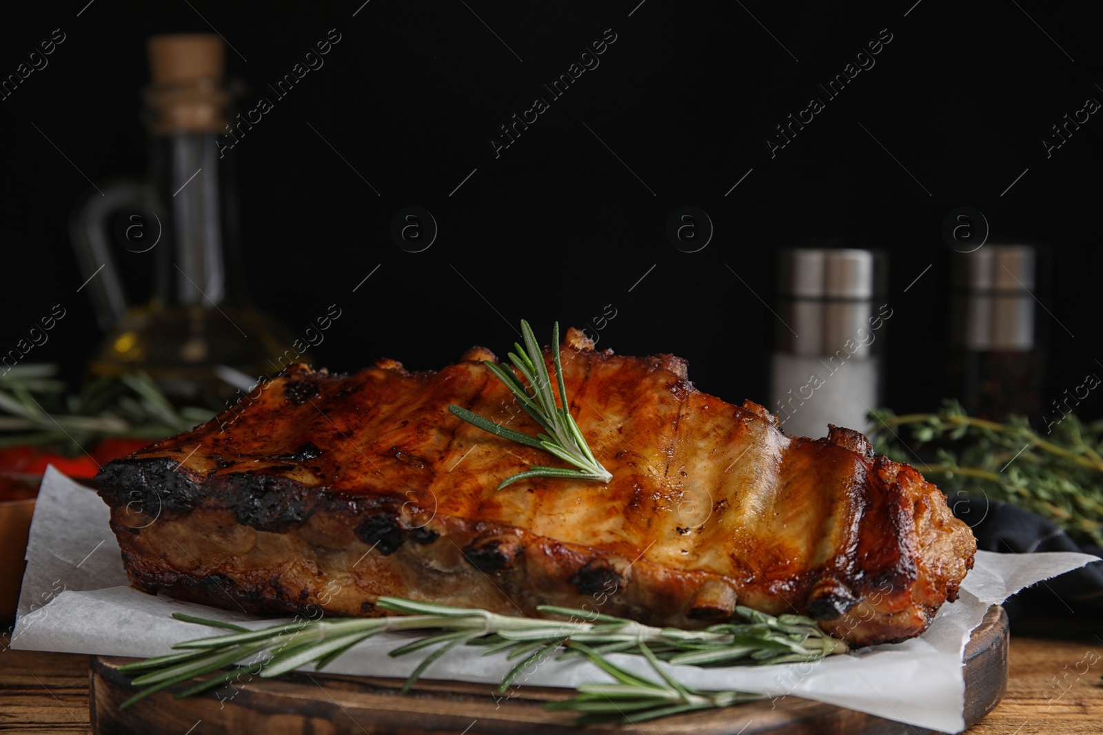 Photo of Tasty grilled ribs with rosemary on wooden table