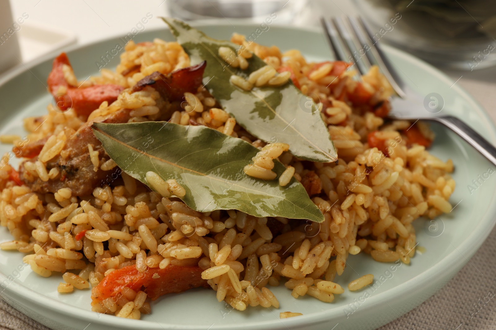 Photo of Delicious pilaf and bay leaves on plate, closeup