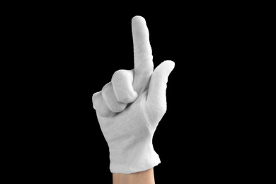 Photo of Person in white glove showing clean finger on black background, closeup