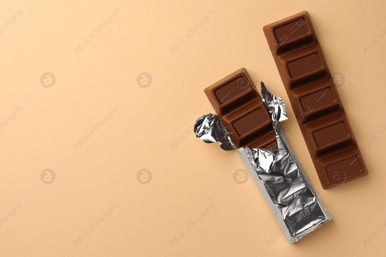 Photo of Delicious chocolate bars on beige background, flat lay. Space for text