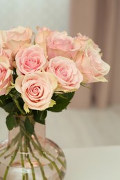 Photo of Beautiful roses in glass vase on table, closeup. Happy birthday greetings