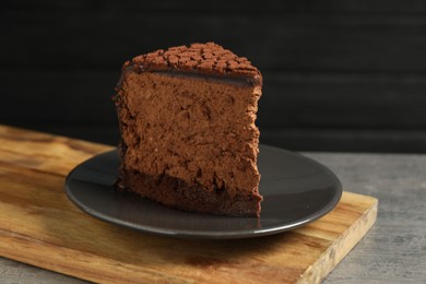 Piece of delicious chocolate truffle cake on grey textured table, closeup