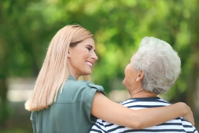 Woman with elderly mother outdoors on sunny day