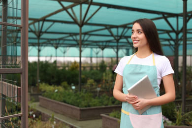 Female business owner with tablet in greenhouse. Space for text