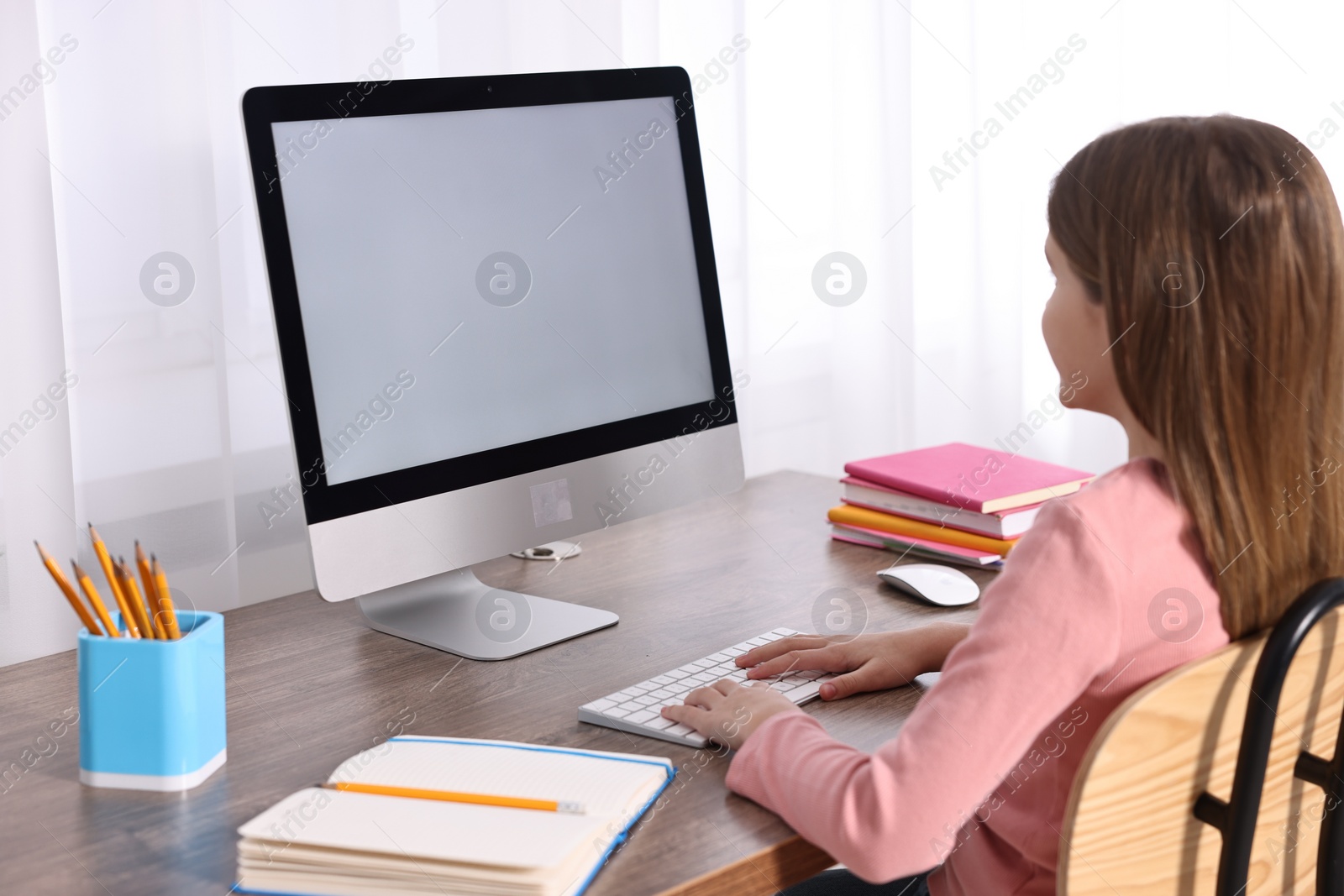 Photo of E-learning. Girl using computer during online lesson at table indoors