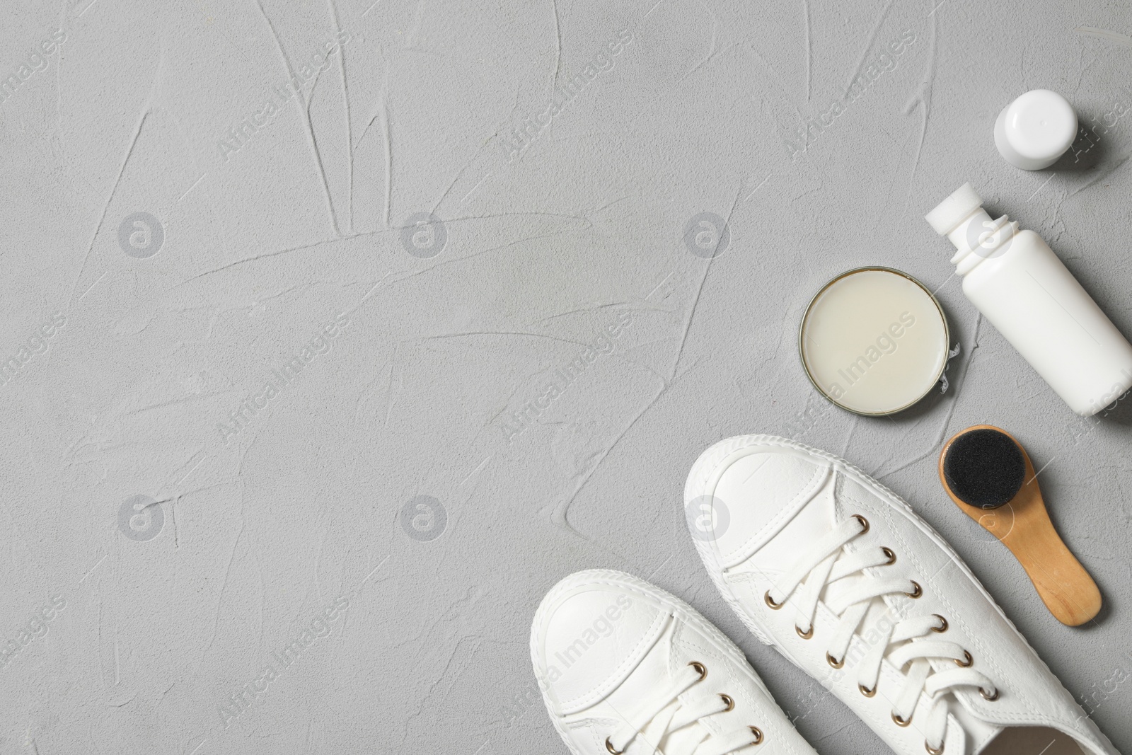 Photo of Flat lay composition with stylish footwear and shoe care accessories on light grey background, space for text