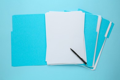 Turquoise files with blank sheets of paper and pen on light blue background, top view. Space for design