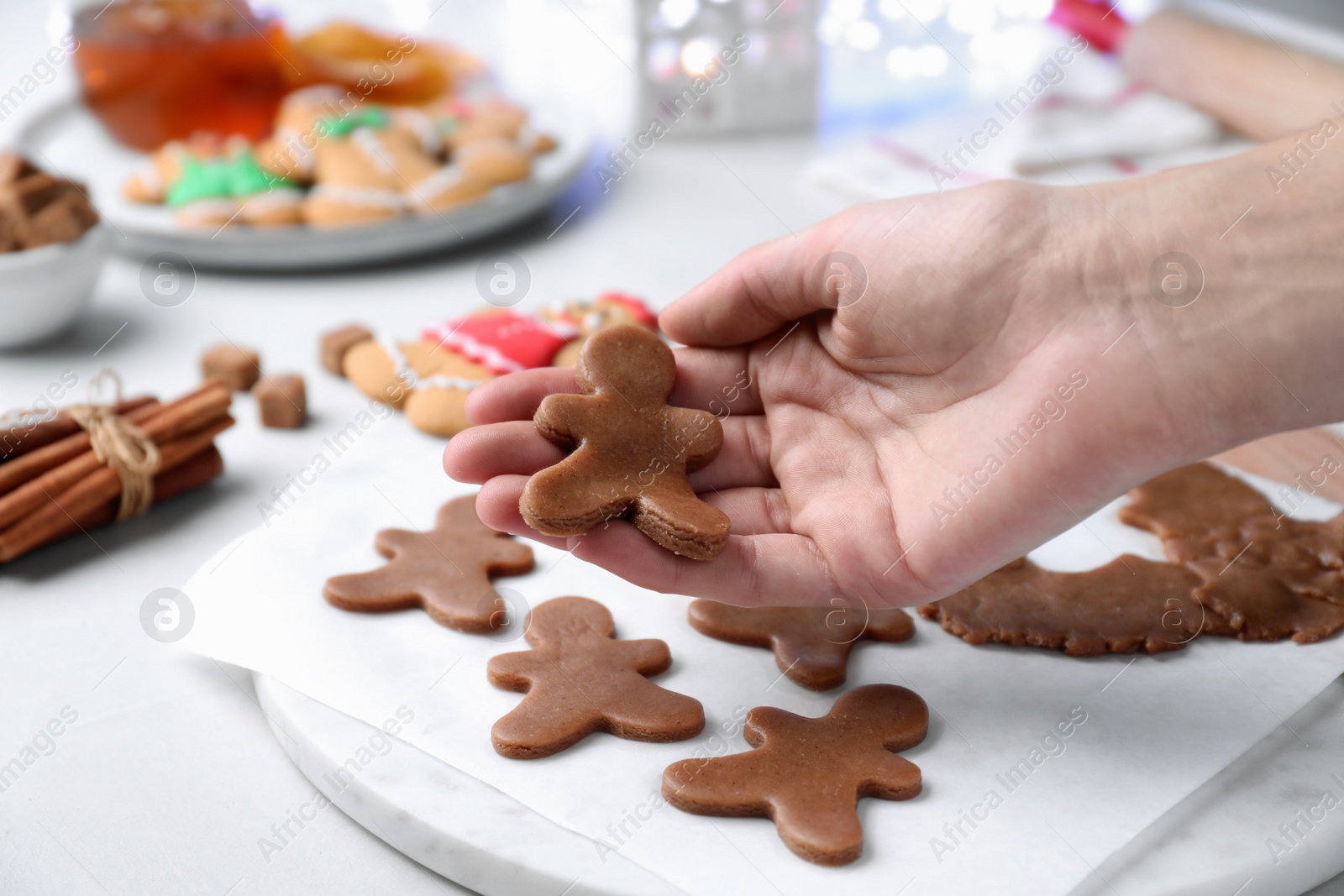 Photo of Making homemade Christmas cookies. Woman holding gingerbread man, closeup