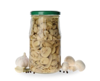 Jar of pickled mushrooms and fresh ingredients on white background