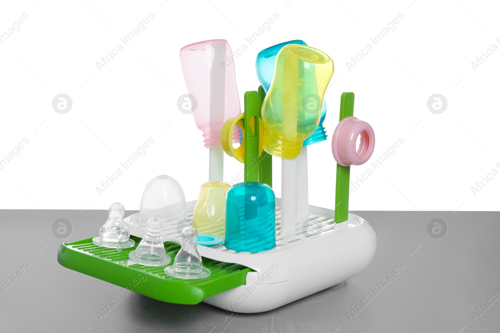 Photo of Dryer with baby bottles and nipples after sterilization on light grey table against white background