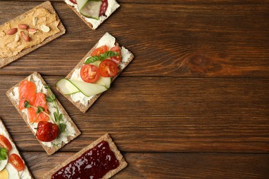 Photo of Fresh rye crispbreads with different toppings on wooden table, flat lay. Space for text