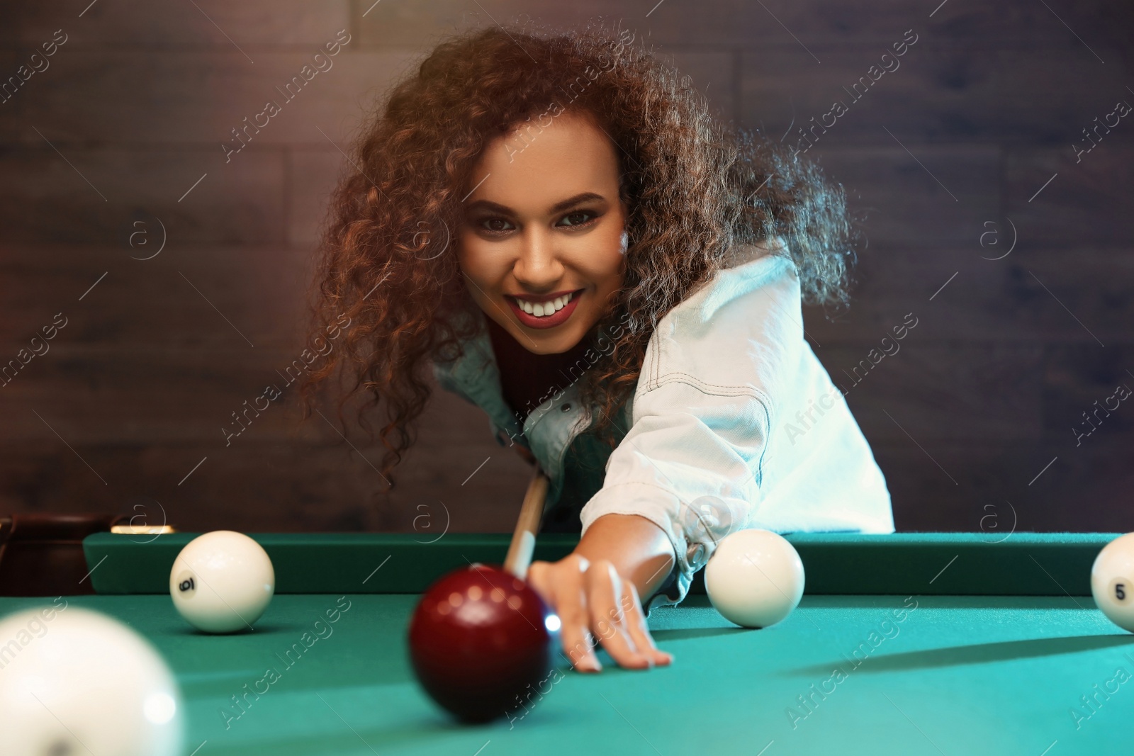 Photo of Young African-American woman playing Russian billiard indoors