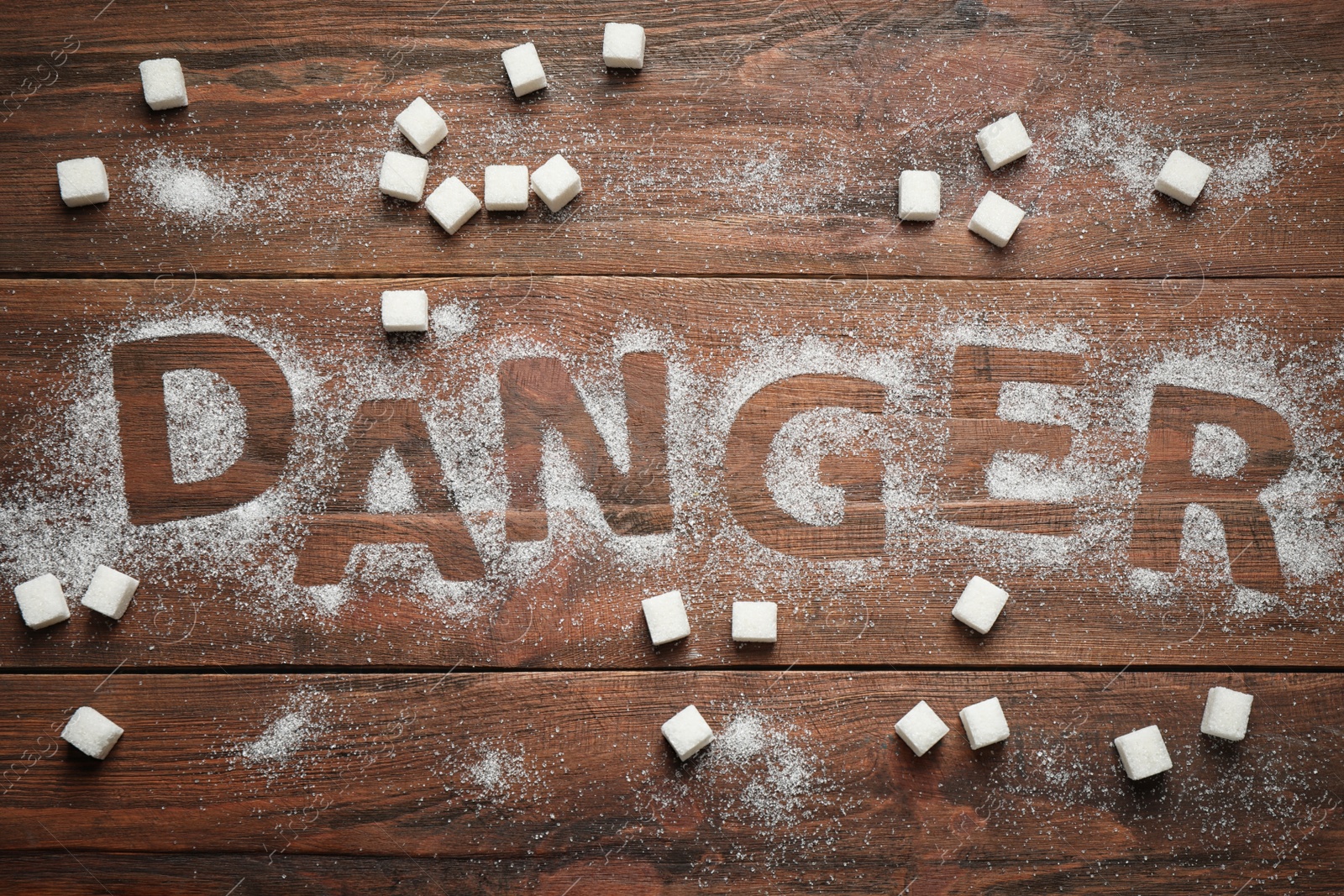 Photo of Flat lay composition with word DANGER and sugar on wooden table