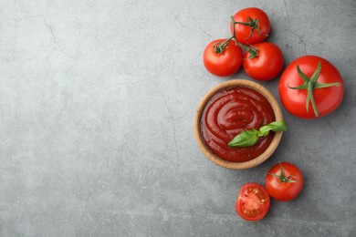 Photo of Bowl of tasty ketchup, tomatoes and basil on light grey table, flat lay. Space for text