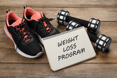 Notebook with phrase Weight Loss Program, sneakers and dumbbells on wooden table