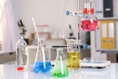 Photo of Laboratory analysis. Glassware with different liquids on white table indoors