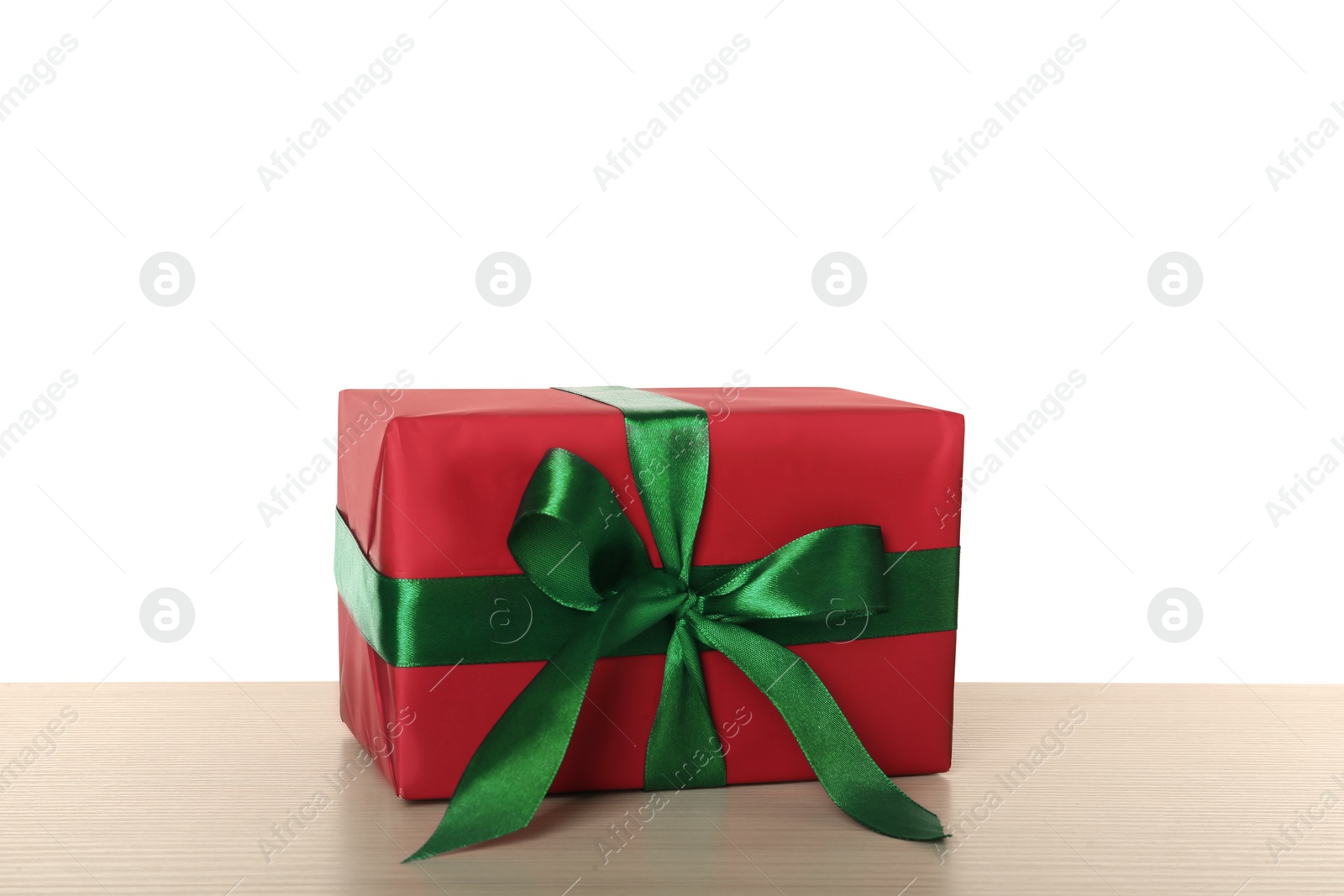 Photo of Red gift box with green bow on wooden table against white background
