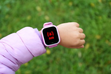 Image of Little girl using SOS function on smartwatch outdoors, closeup