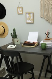Photo of Typewriter and stack of papers on dark table in room. Writer's workplace