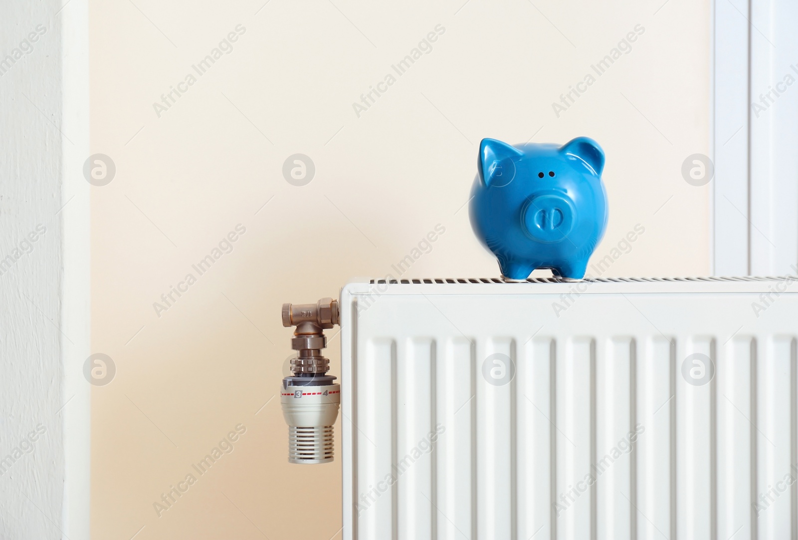 Photo of Piggy bank on modern heating radiator indoors