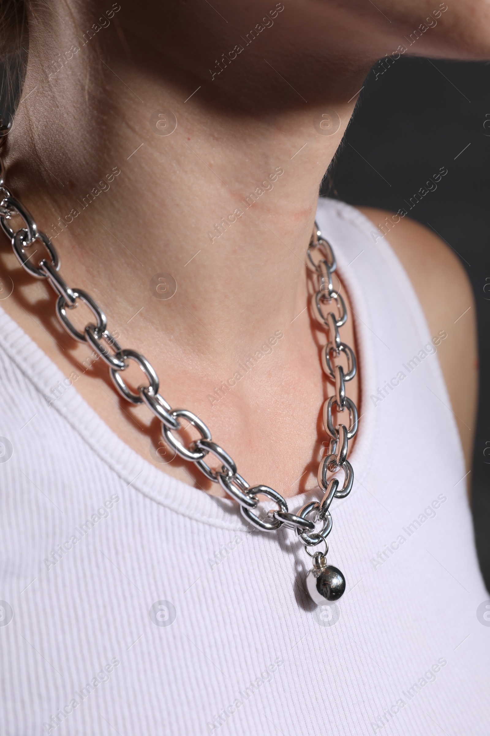 Photo of Woman wearing metal chain with pendant, closeup. Luxury jewelry