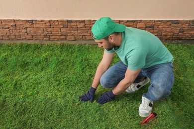 Worker laying grass sod at backyard, space for text