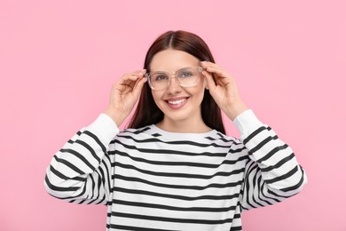 Portrait of smiling woman in stylish eyeglasses on pink background