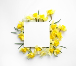 Photo of Beautiful daffodils and card on white background, top view with space for text. Fresh spring flowers