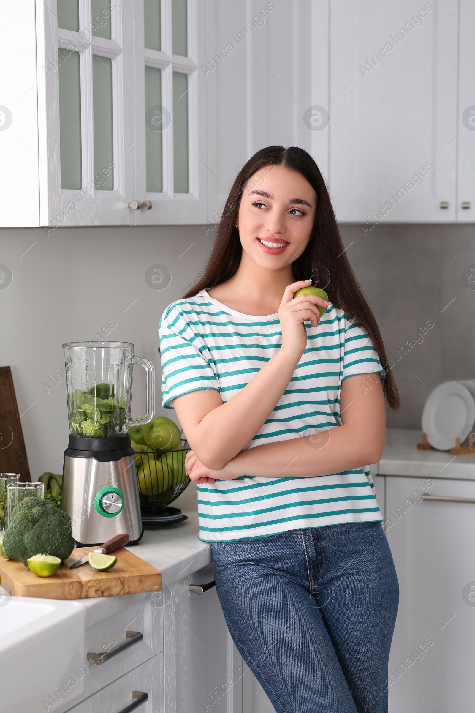 Photo of Beautiful young woman with apples for smoothie in kitchen