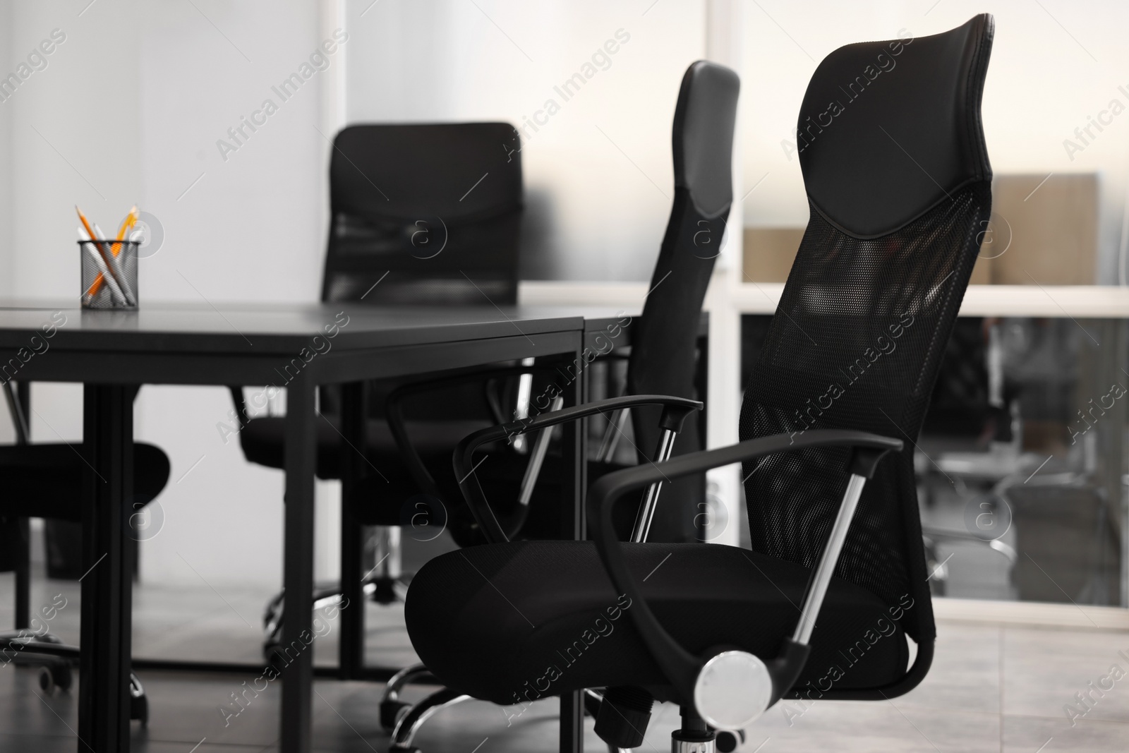Photo of Comfortable office chairs and tables in meeting room, closeup