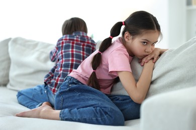 Upset brother and sister on sofa at home