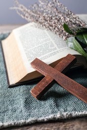 Photo of Wooden cross and Bible on table, closeup