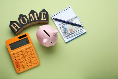 Photo of Flat lay composition with piggy bank and calculator on green background, space for text. Paying bills concept