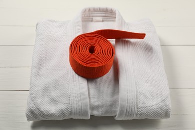 Photo of Orange karate belt and white kimono on wooden background