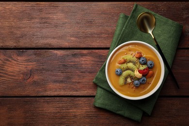 Delicious smoothie bowl with fresh berries, kiwi and nuts on wooden table, flat lay. Space for text