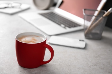 Photo of Red cup with coffee on office table. Space for text