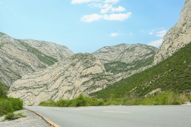 Photo of Beautiful view of mountains and cyclist on asphalt highway. Road trip
