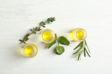 Photo of Bottles with essential oils and fresh herbs on light background, top view