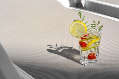 Photo of Delicious refreshing lemonade with raspberries on light gray rattan sunbed, space for text
