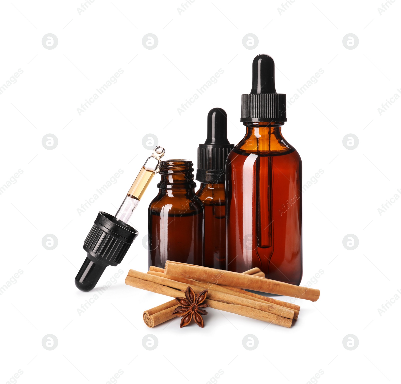 Image of Bottles of natural essential oil, anise and cinnamon sticks on white background