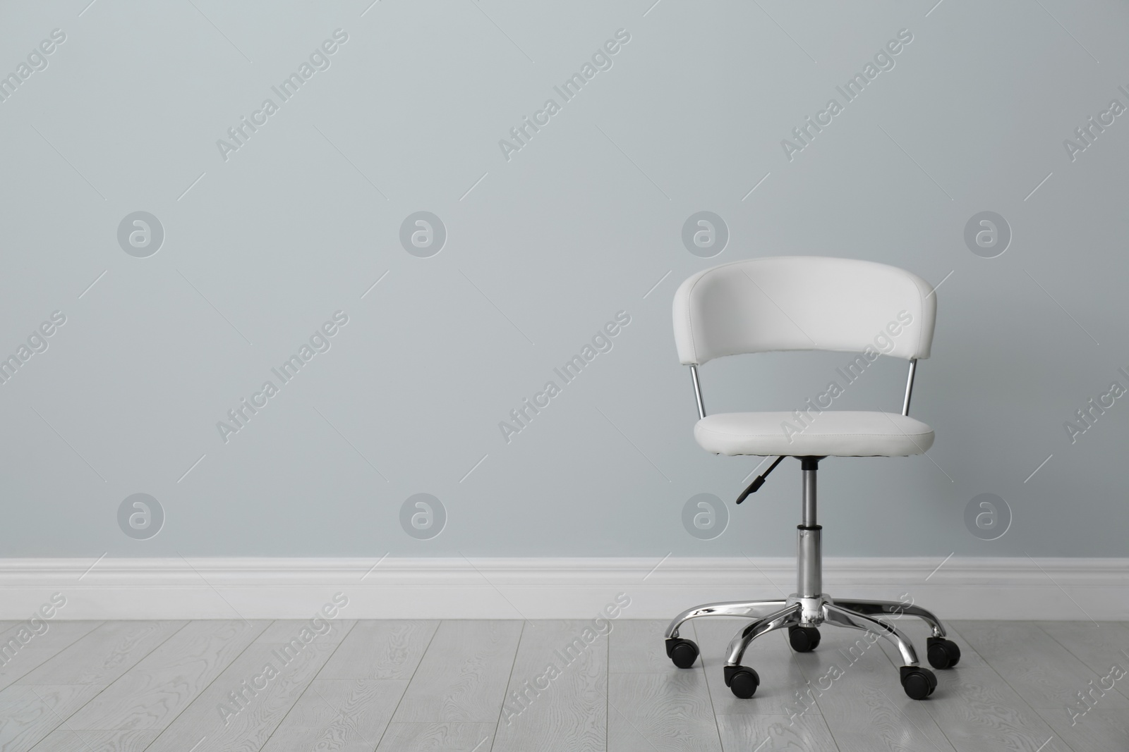 Photo of Comfortable office chair near light wall indoors. Space for text