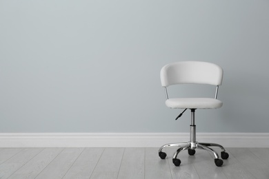 Comfortable office chair near light wall indoors. Space for text