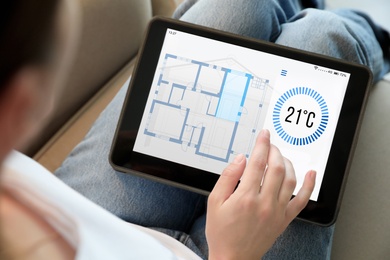 Woman using tablet to control heating system in house, closeup