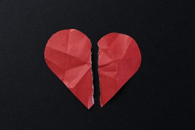 Photo of Halves of torn paper heart on black background, top view. Breakup concept