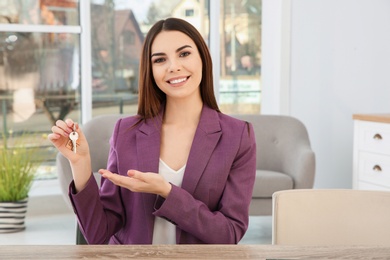 Photo of Young woman holding new house key indoors
