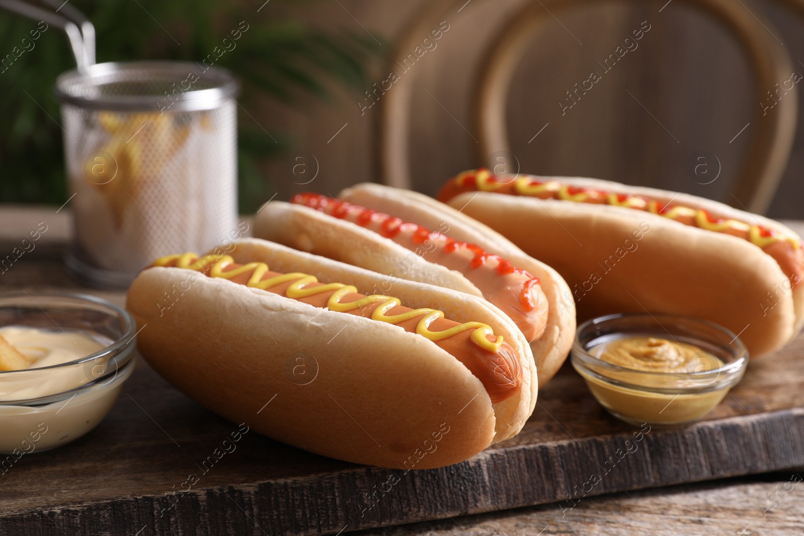 Photo of Delicious hot dogs with sauces on wooden table, closeup